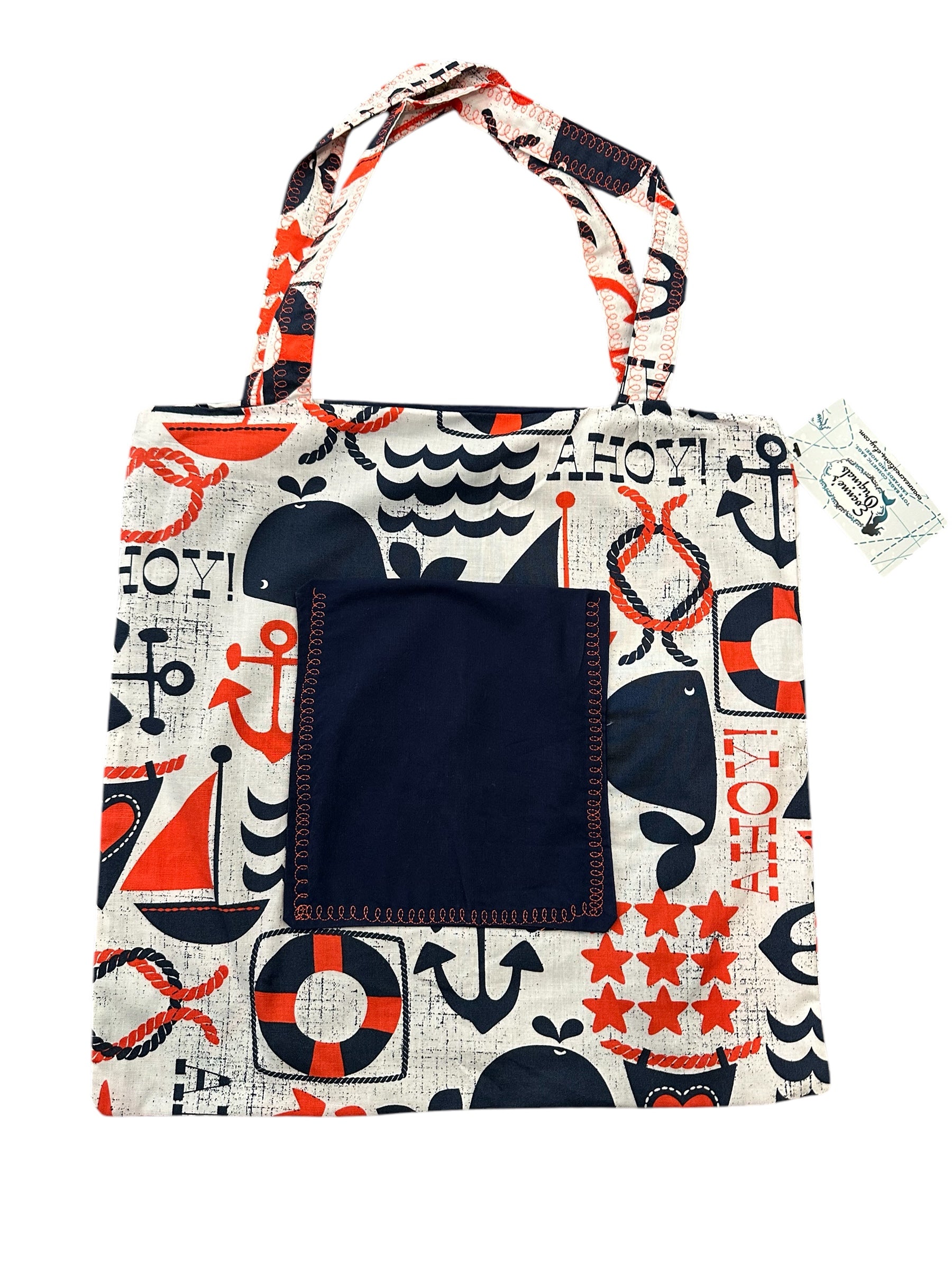 Tote bag with nautical pattern featuring whales, anchors, and life buoys on a white background.
