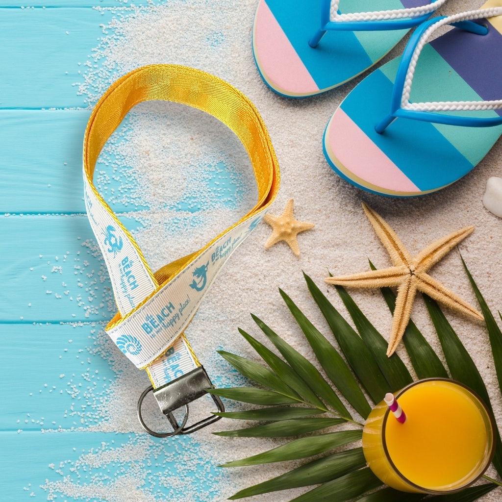Beach-themed lanyard with flip-flops, starfish, and a drink on a sandy surface.